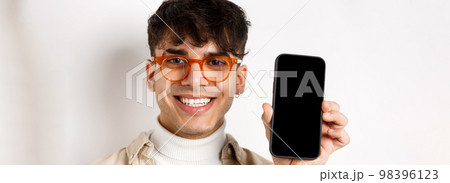 Face of handsome smiling guy in glasses showing empty smartphone scree, white background 98396123
