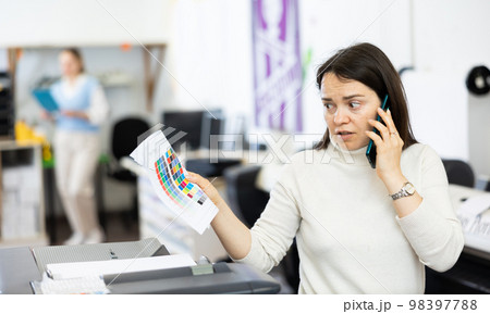 Confused woman printing office manager having telephone conversation 98397788