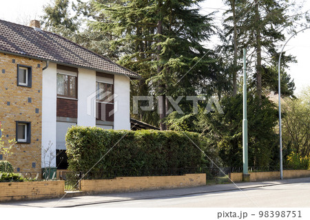 Modern family house on rural street surrounded with green trees Modern family house on rural street surrounded with green trees 98398751