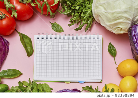 vegetables and a notepad on a pink background with space for your text or image to be written in the notes 98398894