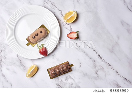 some desserts on a white plate with lemon slices and strawberries in the photo is taken from above it 98398999