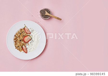 a bowl of cereal and strawberries on a white plate with a wooden spoon next to the bowl is filled with oats 98399145