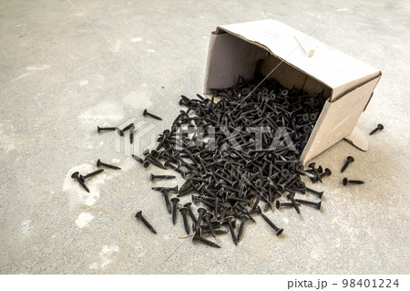 Close-up image of many small black screws on concrete background 98401224