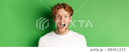 Emotions and fashion concept. Close up of surprised redhead man hear amazing news, staring at camera joyful, standing over green background Emotions and fashion concept. Close up of surprised redhead man hear amazing news, staring at camera joyful, standing over green background 98401335