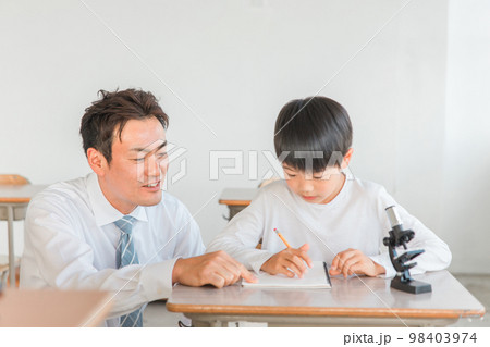 学校の授業で理科の実験・観察・研究・勉強をする小学生の男の子と先生・教師(顕微鏡) 98403974