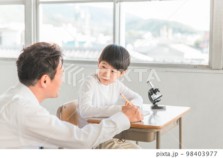 学校の授業で理科の実験・観察・研究・勉強をする小学生の男の子と先生・教師(顕微鏡) 98403977