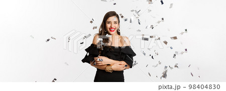 Happy woman celebrating winter holidays, smiling cheerful, partying on New Year with confetti, standing over white background 98404830