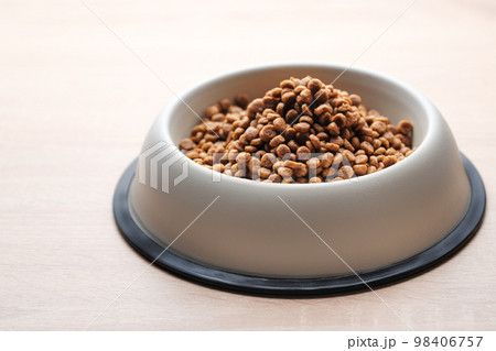 A bowl of dog food on a wooden floor. 98406757