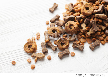 Dry food for dogs of different shapes on a white wooden background. 98406760