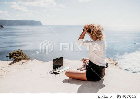Woman sea laptop yoga. Business woman freelancer in yoga pose working over blue sea beach at laptop and meditates. Girl relieves stress from work. Freelance, digital nomad, travel and holidays concept Woman sea laptop yoga. Business woman freelancer in yoga pose working over blue sea beach at laptop and meditates. Girl relieves stress from work. Freelance, digital nomad, travel and holidays concept 98407015