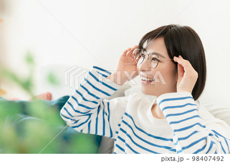 リビングでメガネをかける若い女性 リビングでメガネをかける若い女性 98407492