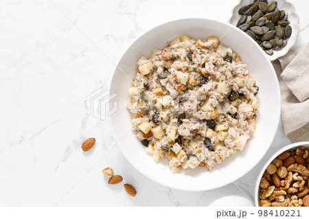 Oatmeal bowl. Oat porridge with nuts, apple, chia seeds and pumpkin seeds for healthy breakfast or lunch. Healthy vegan food, diet. Top view Oatmeal bowl. Oat porridge with nuts, apple, chia seeds and pumpkin seeds for healthy breakfast or lunch. Healthy vegan food, diet. Top view 98410221