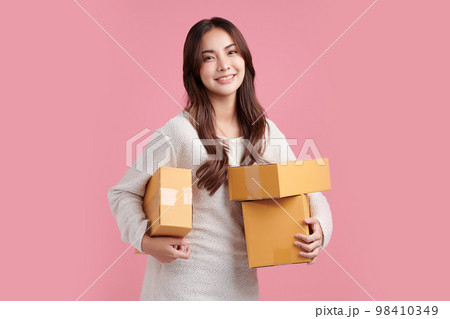 Beautiful Young Asian woman holding parcel box isolated on pink background, Delivery courier and shipping service concept. Beautiful Young Asian woman holding parcel box isolated on pink background, Delivery courier and shipping service concept. 98410349