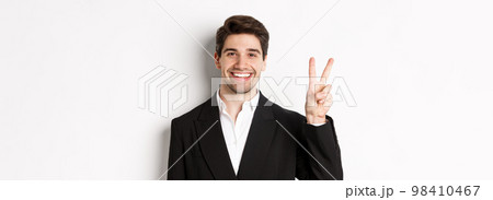 Close-up of handsome businessman in black suit, smiling amazed, showing number two, standing over white background Close-up of handsome businessman in black suit, smiling amazed, showing number two, standing over white background 98410467