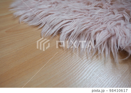 Long pile rug in pink on a beige laminate floor. Feminine interior for a room or bedroom of a girl or woman. Interior design in pink tones. Flooring is laminate. The role of dust mites in allergies. 98410617
