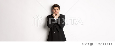 Image of scared and insecure young businessman in suit, trembling from fear and looking horrified, standing over white background Image of scared and insecure young businessman in suit, trembling from fear and looking horrified, standing over white background 98411513