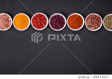 Composition consisting of variations of spices in white bowls and metal spoons 98413017