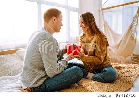 Valentine's Day concept. Exchange of gifts. Young couple at home celebrating Valentine's Day. 98413710
