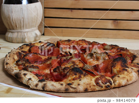 Fresh Pizza on Wooden Table at Restaurant With Bottle of Chianti Wine in Background Fresh Pizza on Wooden Table at Restaurant With Bottle of Chianti Wine in Background 98414079