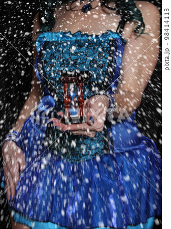 Woman in blue corset with hourglass in hands and snow falling Woman in blue corset with hourglass in hands and snow falling 98414113