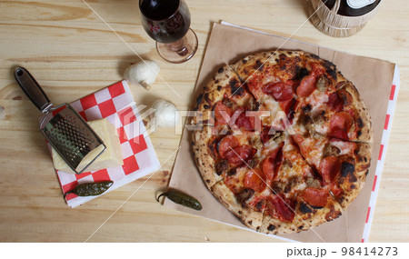 Fresh Pizza on Wooden Table at Restaurant With Bottle of Chianti Wine in Background Fresh Pizza on Wooden Table at Restaurant With Bottle of Chianti Wine in Background 98414273