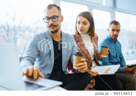 Colleagues with coffee are discussing a new business project in creative office. Planning, study. 98414652