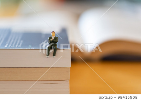 机の上に開いた英語の書籍 研究 学習 学び直しのイメージ スーツの男性フィギア  98415908
