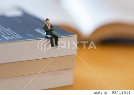 机の上に開いた英語の書籍 研究 学習 学び直しのイメージ スーツの男性フィギア  98415911