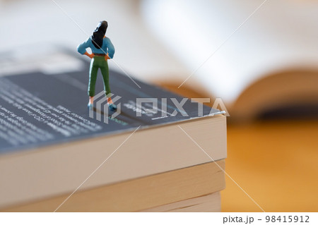 机の上に開いた英語の書籍 研究 学習 学び直しのイメージ 女性フィギア  98415912