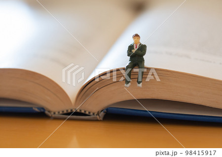 机の上に開いた英語の書籍 研究 学習 学び直しのイメージ スーツの男性フィギア  98415917