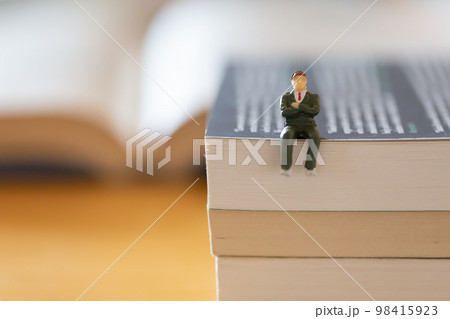 机の上に開いた英語の書籍 研究 学習 学び直しのイメージ スーツの男性フィギア  98415923