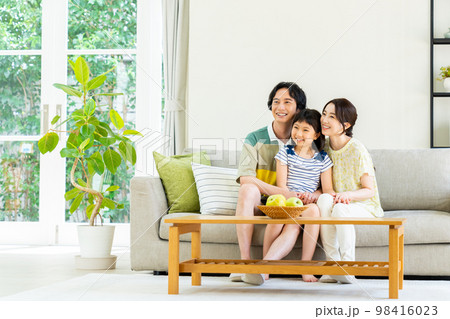 リビングでくつろぐ若い家族 98416023