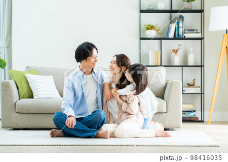 リビングでくつろぐ若い家族 98416035