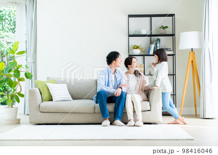 リビングでくつろぐ若い家族 98416046