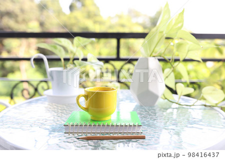 Yellow coffee cup and pothos neon plant on glass table 98416437