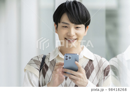 スマートフォンを持った笑顔の若い男性 98418268