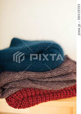 A stack of knitted woolen products lies on a wooden stool 98419593