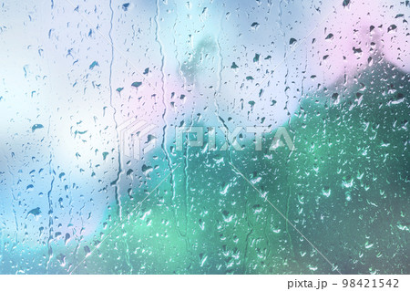 Water drops run down glass window. Abstract blurred background with lights bokeh. Condensation on window. Defocused backdrop of city street in rainy sunset. View through window Water drops run down glass window. Abstract blurred background with lights bokeh. Condensation on window. Defocused backdrop of city street in rainy sunset. View through window 98421542