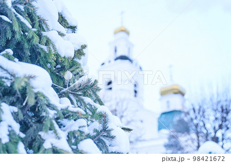 Christmas background. The gilded upper part of the Orthodox Christian church against the background of blue sky and snow-covered fir branches. Space for copying. High quality photo 98421672