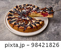 Piece of plum tart on shoulder blade and pie on plate, close up 98421826