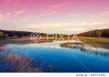 Magical sunrise over the lake with a beautiful reflection on the water. Serene lake in the early morning. Nature landscape. Aerial view Magical sunrise over the lake with a beautiful reflection on the water. Serene lake in the early morning. Nature landscape. Aerial view 98421837