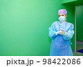 A female doctor in a surgical uniform pulls sterile gloves on her hand.  98422086