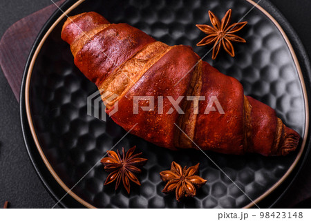 Delicious crispy croissant with chocolate on a black ceramic plate 98423148
