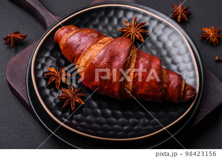 Delicious crispy croissant with chocolate on a black ceramic plate 98423156