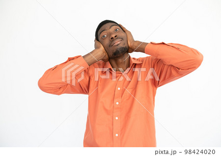 Portrait of happy young man covering ears with hands 98424020