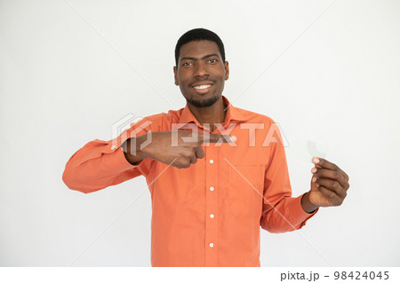 Portrait of positive young man pointing at credit card Portrait of positive young man pointing at credit card 98424045