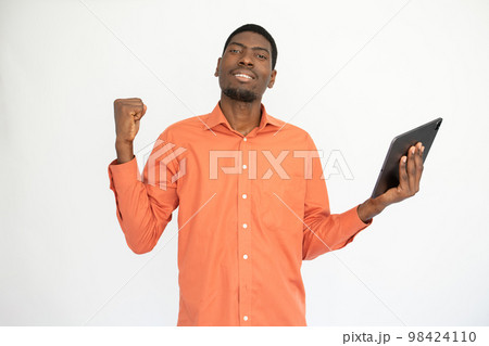 Portrait of happy young man with touchpad making winning gesture Portrait of happy young man with touchpad making winning gesture 98424110