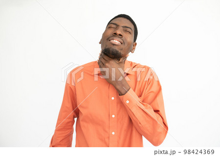 Portrait of displeased young man suffering from sore throat Portrait of displeased young man suffering from sore throat 98424369