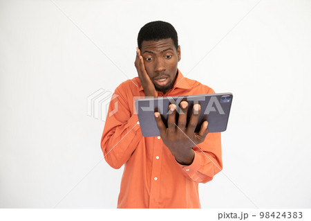 Portrait of worried young man reading news on digital tablet 98424383