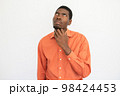 Portrait of pensive young man rubbing chin 98424453